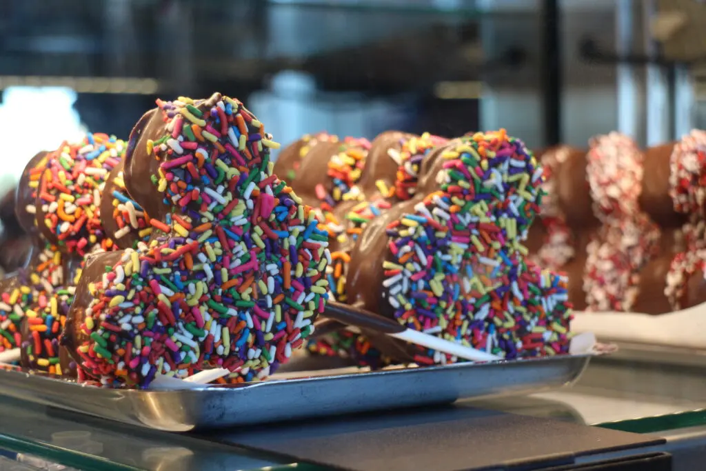 Mickey shaped chocolate treat on a stick covered in rainbow sprinkles