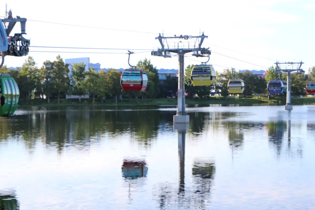 Disney Skyliner gondolas reflecting over water.