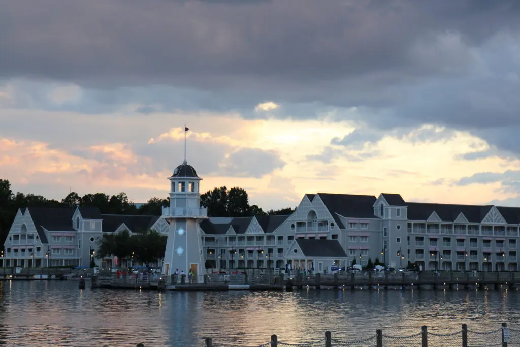 A sunset sky over the yacht club themed Disney resort with a dock and lighthouse.