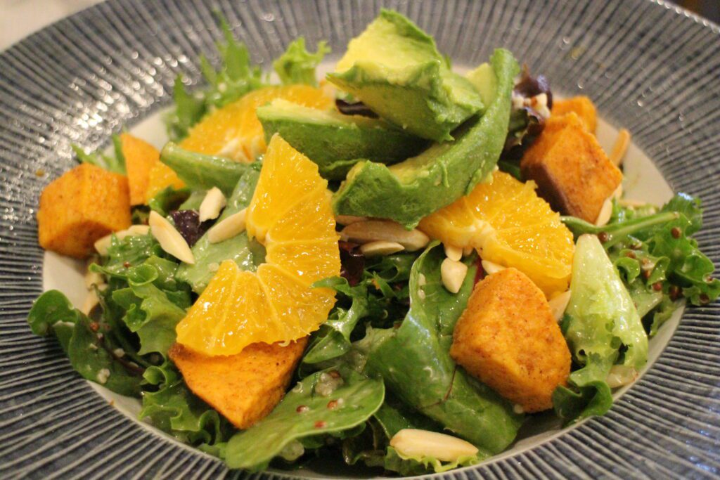 Olivia's Cafe seasonal salad pictured with Mixed Greens, Quinoa, Avocado, Edamame, Orange, and Key Lime Vinaigrette.