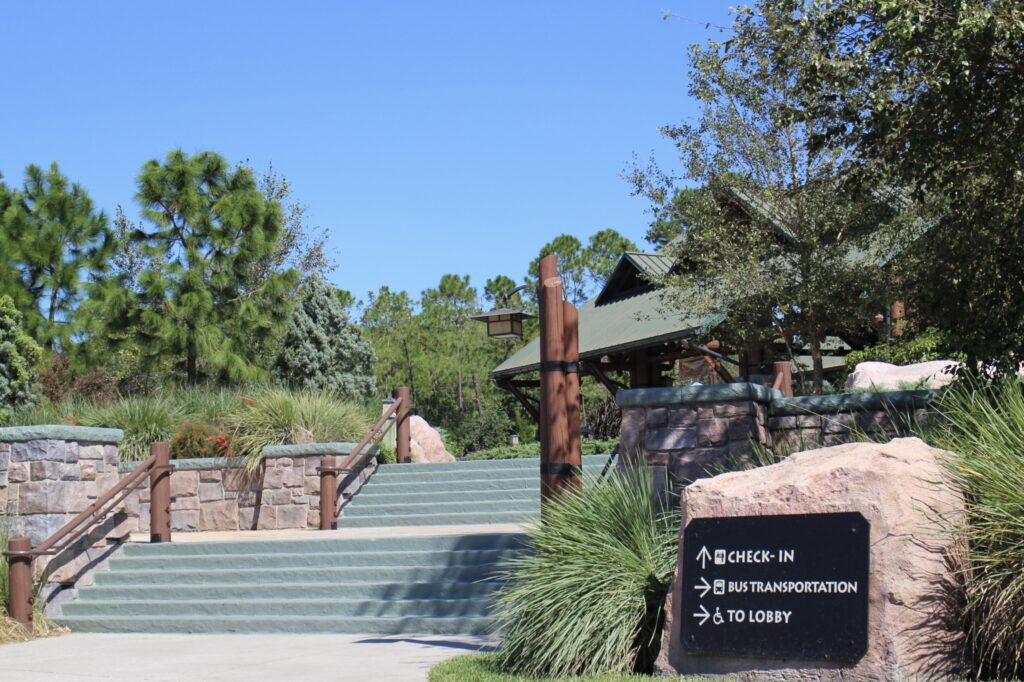 Green steps with a wooded railing leading up to the rustic structure of Disney's Wilderness Lodge, a property with two home resorts on the DVC resale market