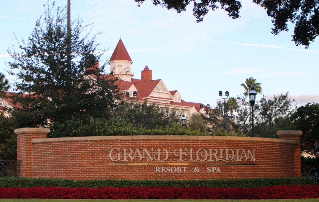 The red brick Grand Floridian Resort and Spa entrance sign with red poinsettias below it.