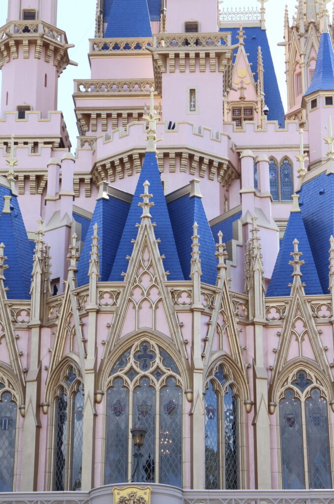 an ornate Cinderella Castle close up with gold adornments, blue rooftops and a light pinkish exterior