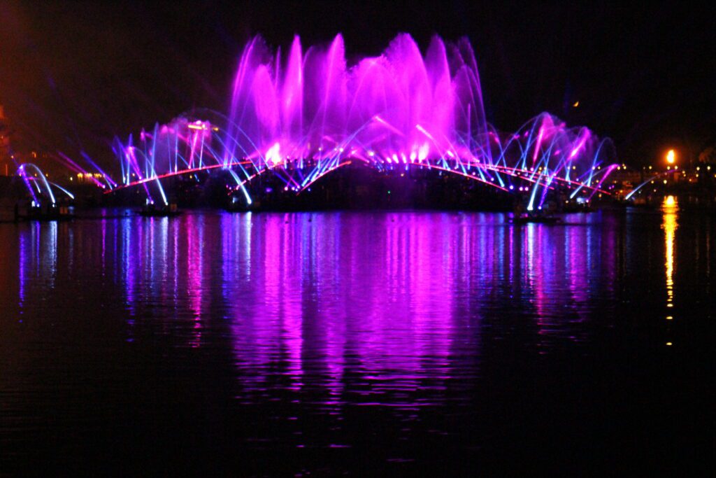 pink and purple fountains over World Showcase Lagoon at night