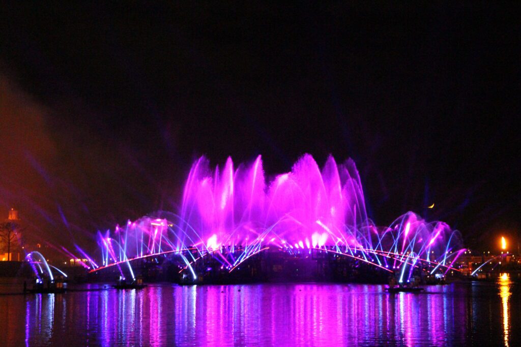 pink and purple fountains reflect at night in World Showcase Lagoon after Luminous fireworks