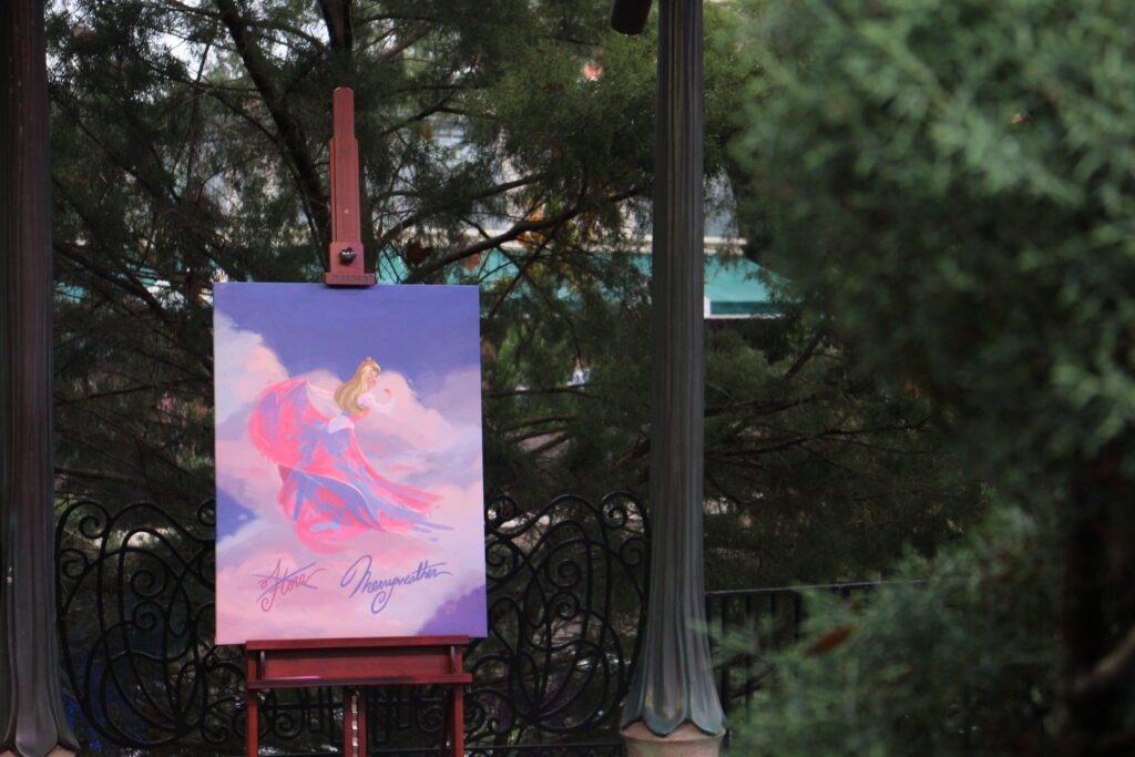 art on an easel of Sleeping Beauty in the clouds with a pink and blue dress