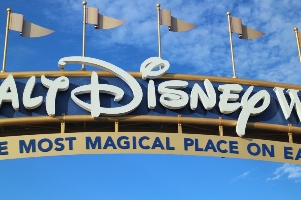 a close up of Disney on the Walt Disney World entrance sign in front of a blue sky