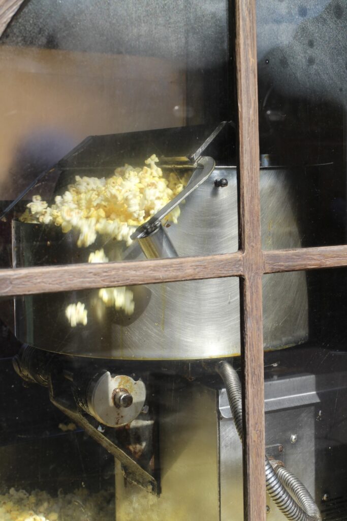 A close up of a popcorn maker with popcorn popping out.