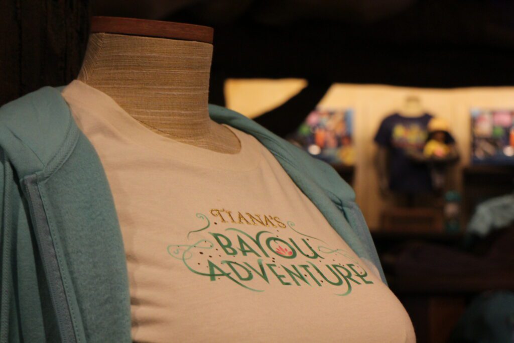 A white shirt that says Tiana's Bayou Adventure in embroidery on a mannequin.