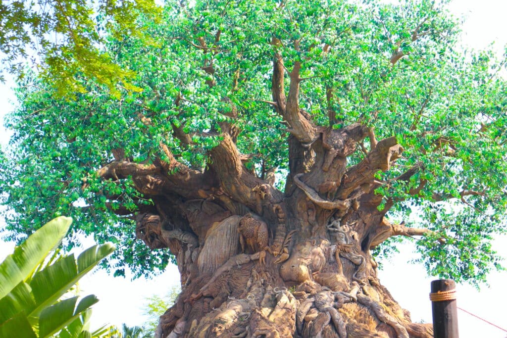 Tree of Life with bright green artificial leaves up top and animals carved into the base.