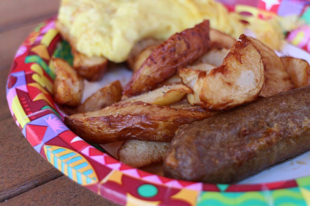 A breakfast platter from the Disney Polynesian restaurant Capt. Cook's with hearty potatoes, a sausage link and eggs.