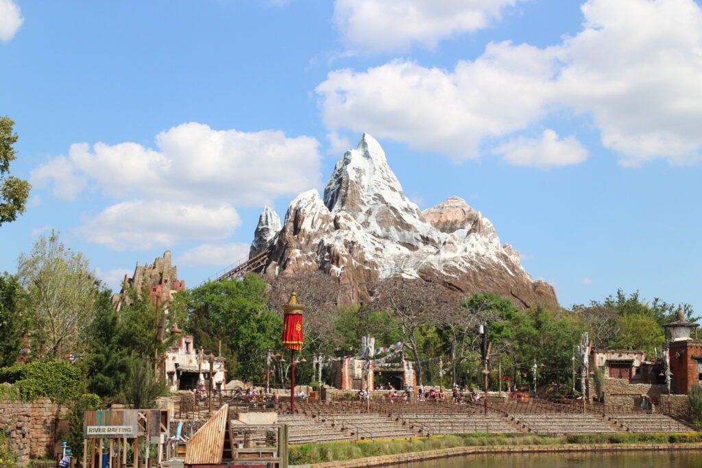 The mountain that looks like Mount Everest at Animal Kingdom with snow covered tops in front of a blue sky with clouds.