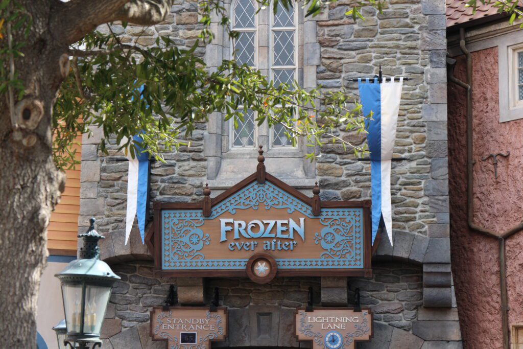 The front of the Frozen ride at Disney World in Epcot. A stone building front with the attraction name Frozen Ever After on an ornate, Norwegian style sign.