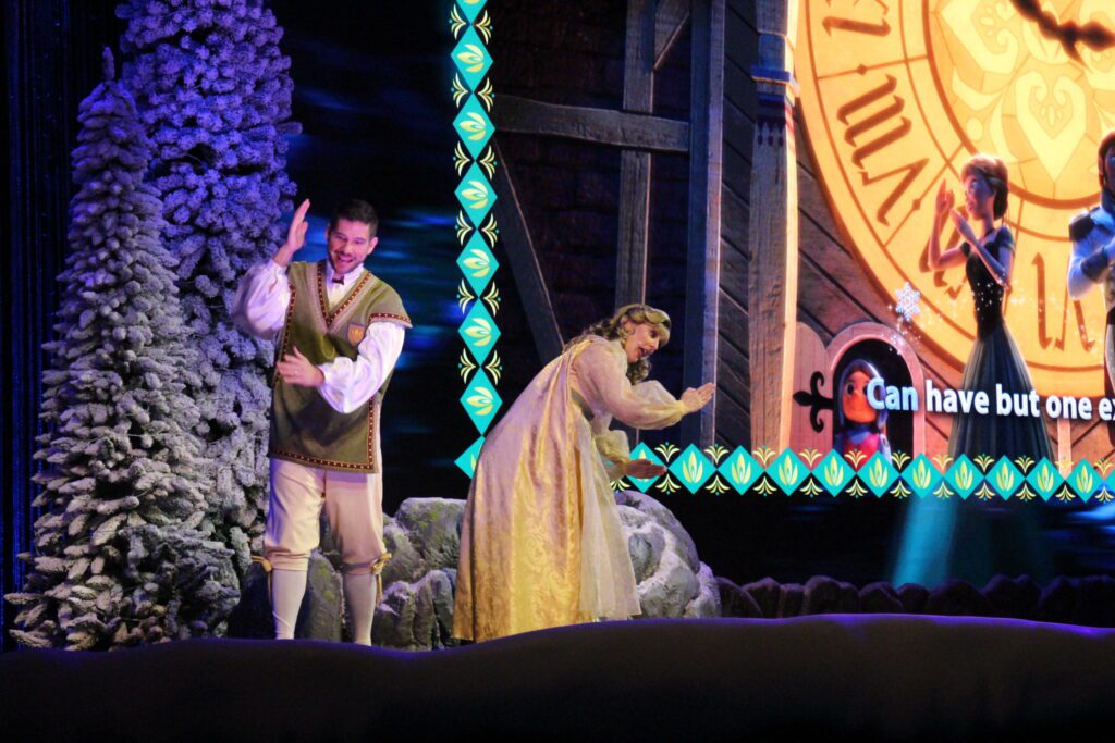 The Arendelle historians dance to Love is an Open Door on stage at the Frozen Singalong show, doing robotic arms like Anna does in the film.