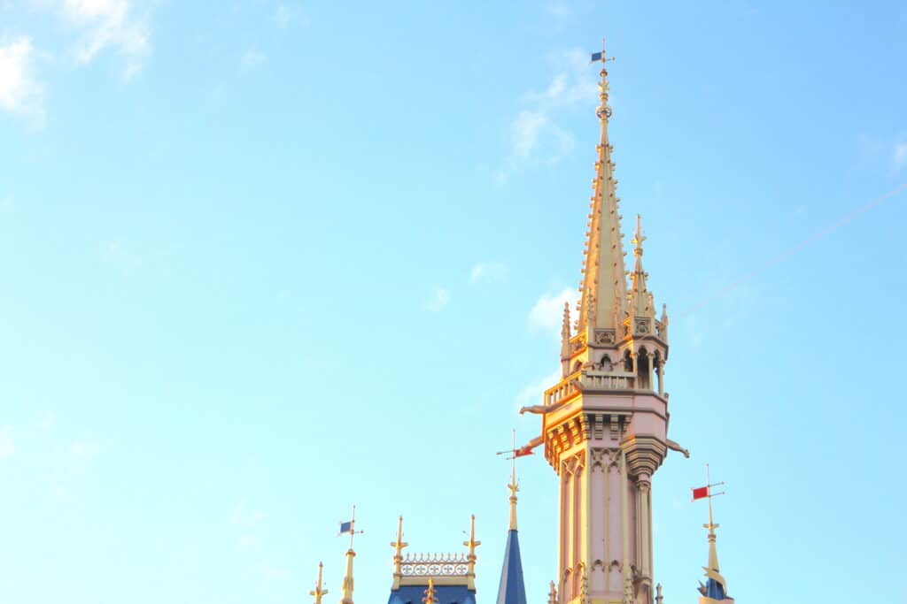 Golden Magic Kingdom castle top in front of a blue sky.