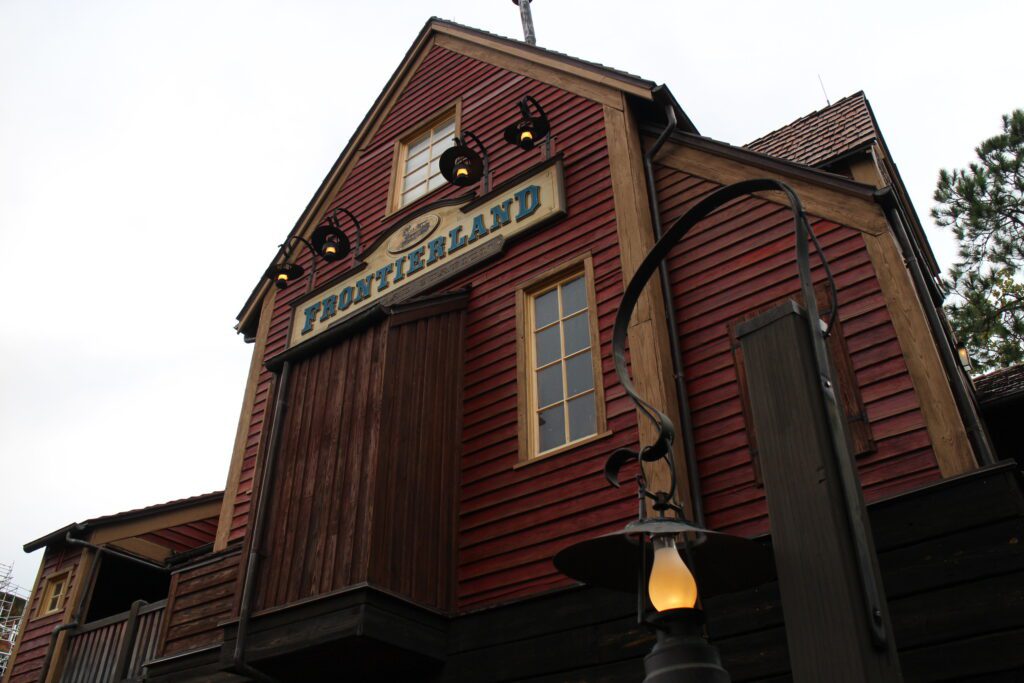 A red old time style building with a sign on it that says Frontierland.