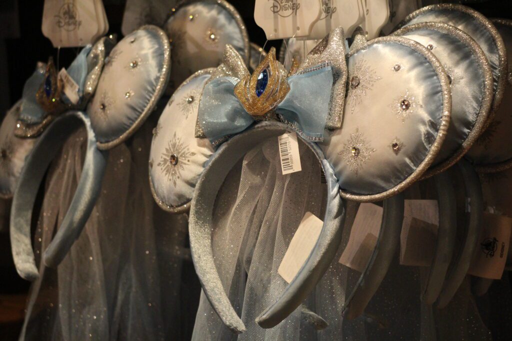 Frozen Elsa ears at Disney World, a silvery blue with snowflakes and some rhinestones on the ears and Elsa's queen crown in the center of the bow.