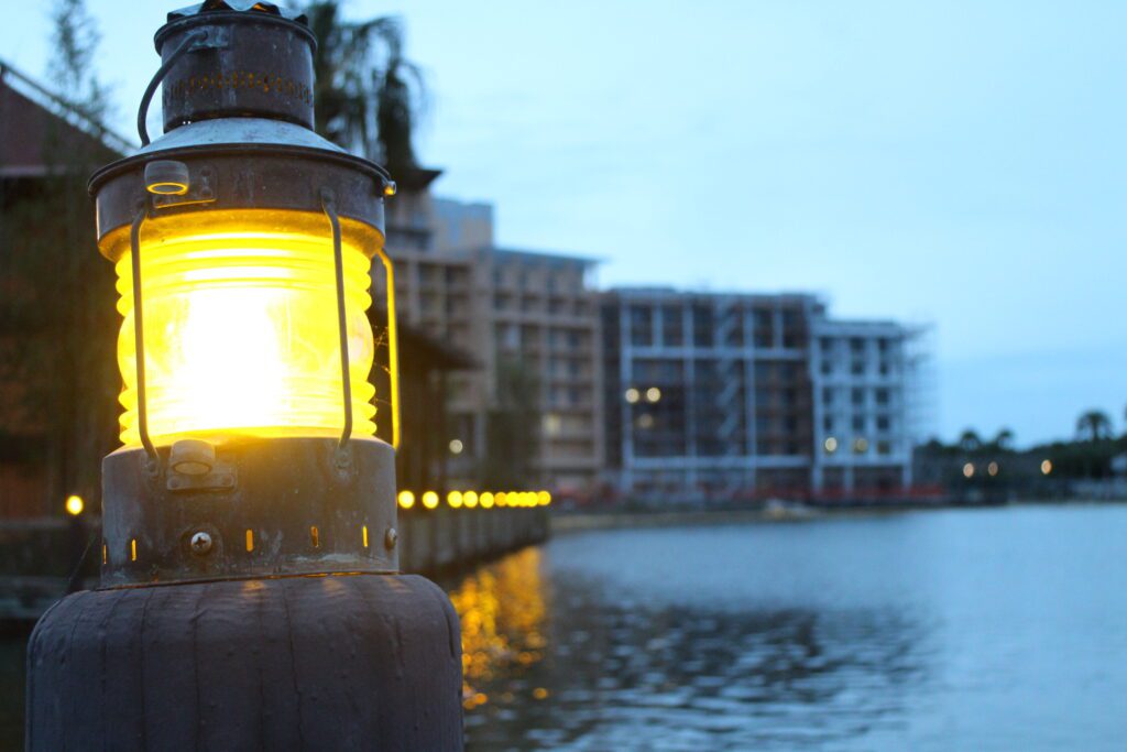 A lantern shines on the Polynesian marina with the Island Tower in the background.