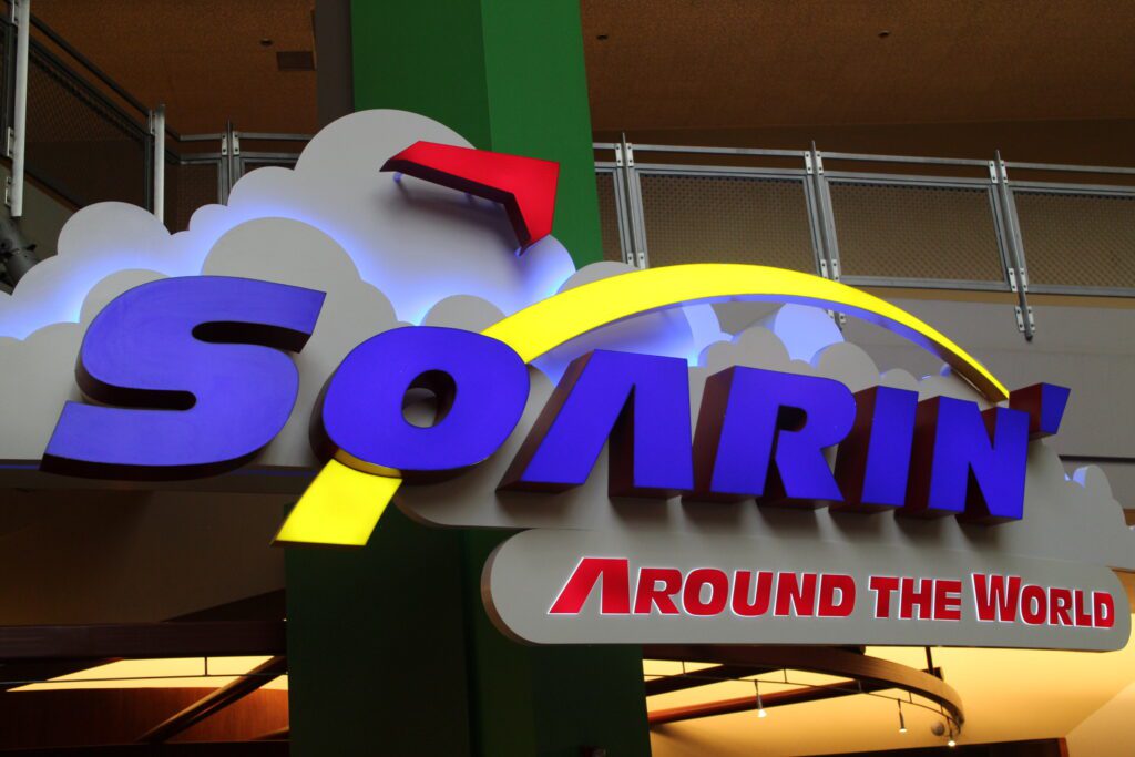 The Soarin' Around the World entrance sign with a hang glider icon and clouds.