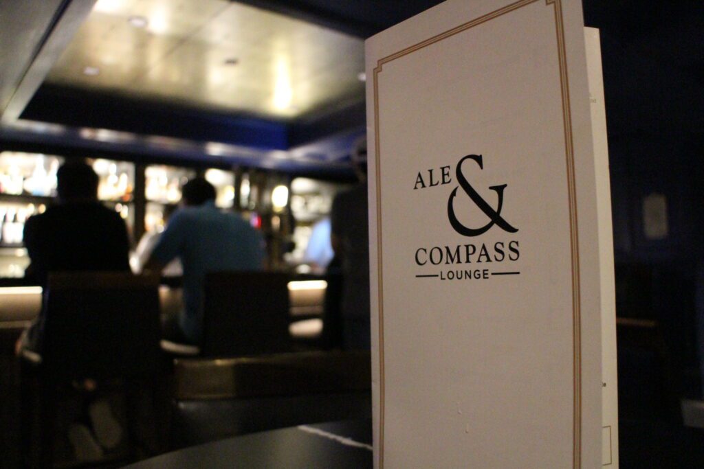 Ale & Compass menu on a table in front of the dark and moody bar.