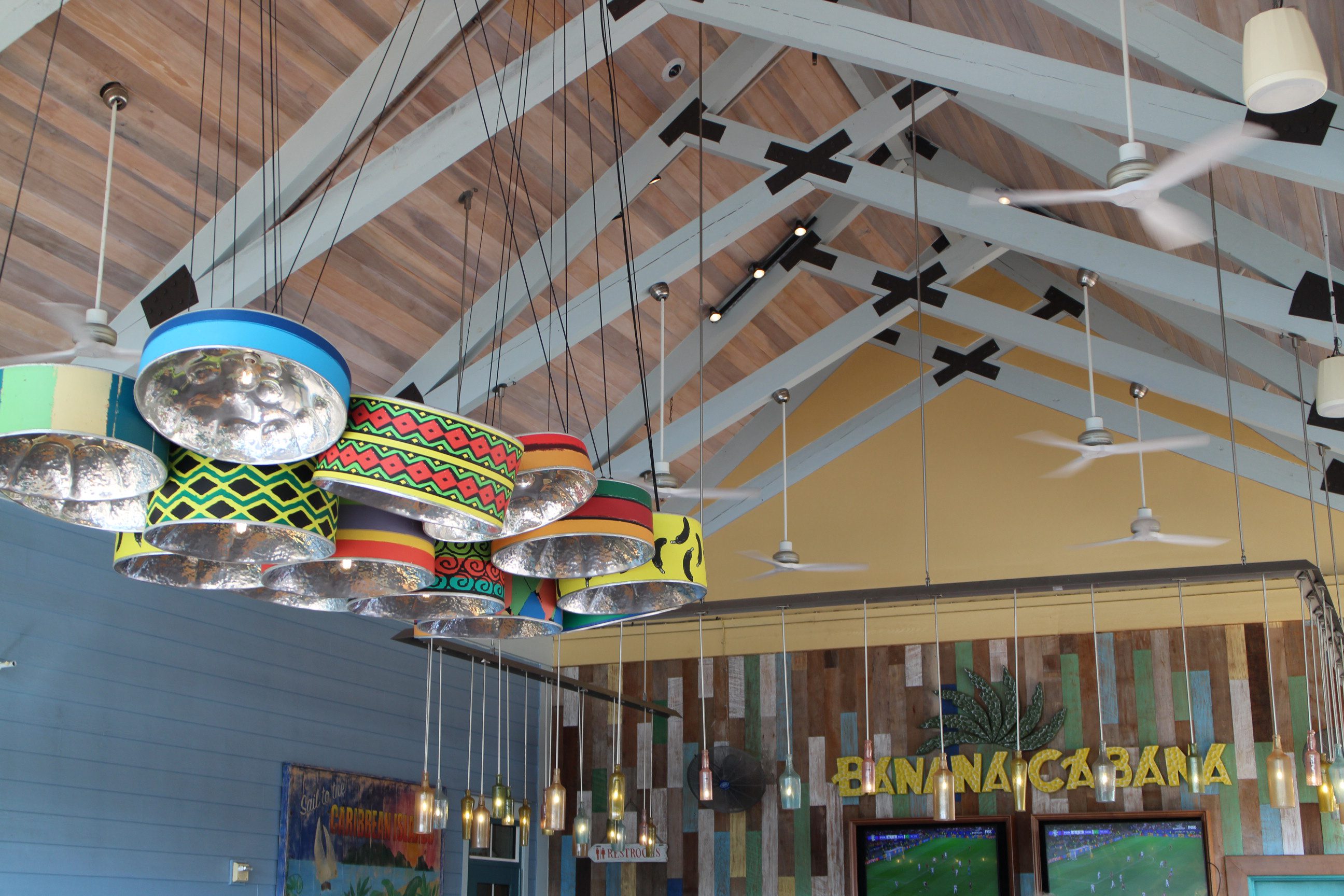 Banana Cabana Bar ceiling with a steel drum chandelier, hanging glass bottles and a pitched roof. Disney Skyliner Bar Crawl.