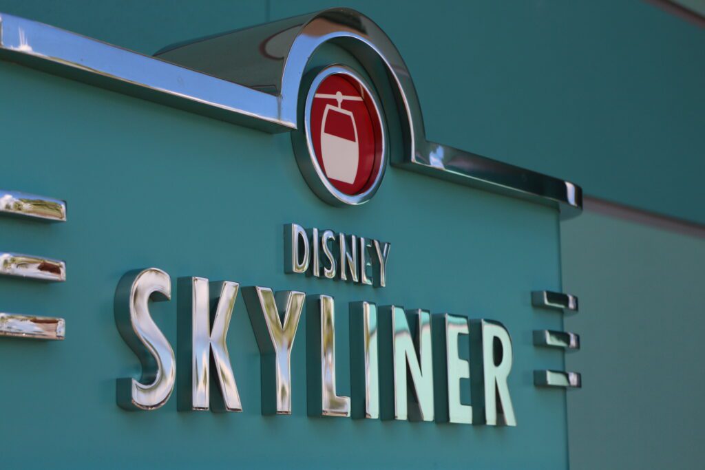 Disney Skyliner sign with silver letters on a teal background.