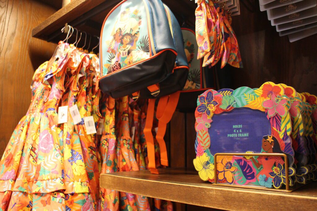 Colorful Encanto merchandise including a picture frame, back pack and girls' dress.