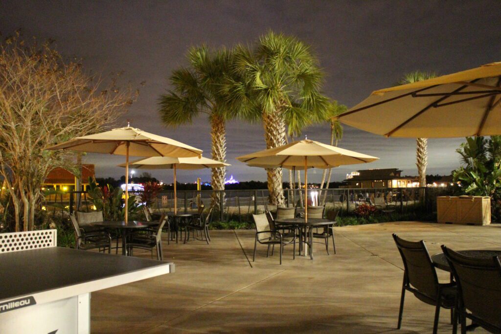 Polynesian resort pool bar seating at night with umbrellas and Magic Kingdom lights off in the background.