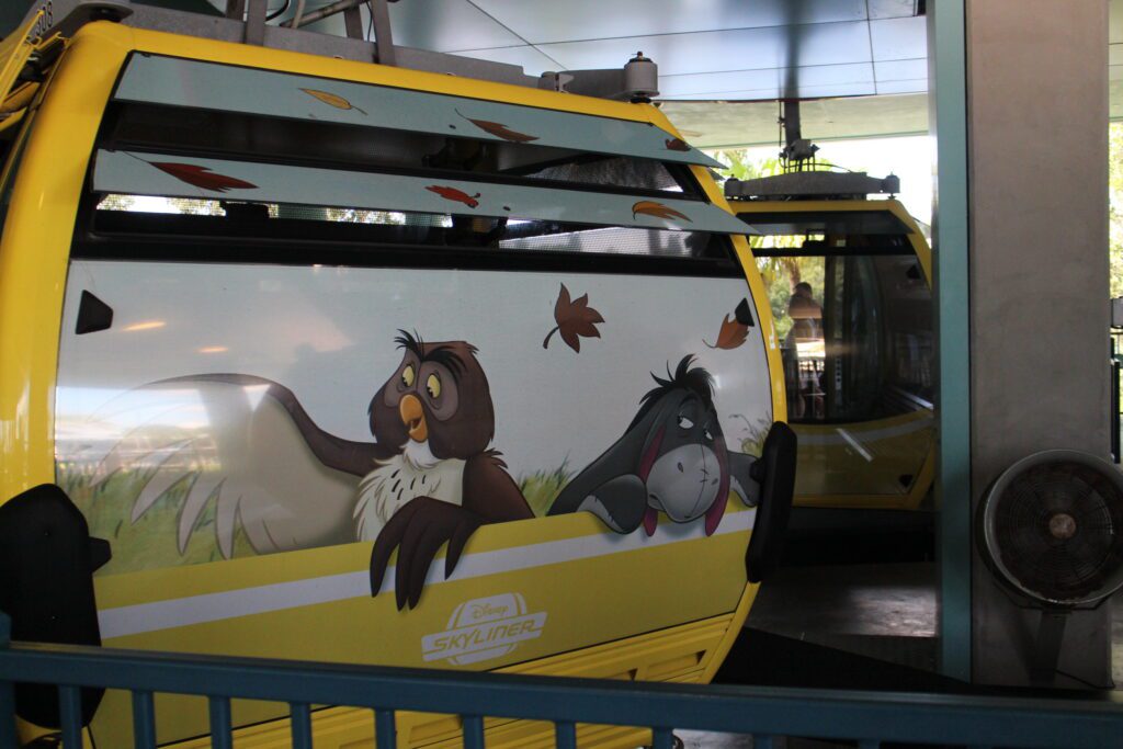 Owl and Eeyore on the side of a yellow hanging gondola on the Skyliner.