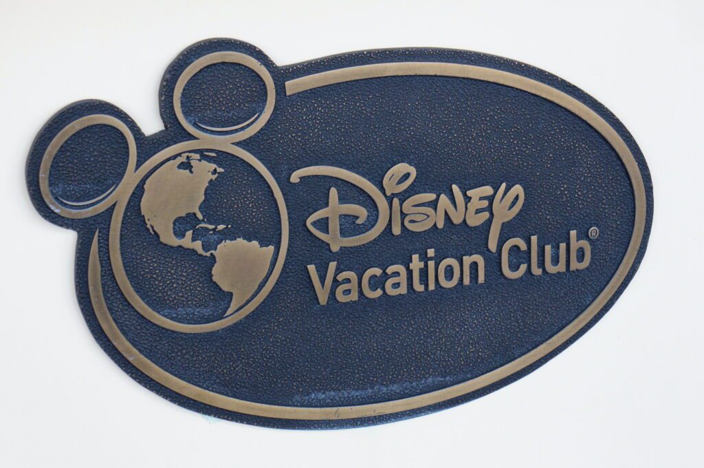 A bronze Disney Vacation Club Membership sign with a globe logo that has mouse ears. Selling DVC Membership