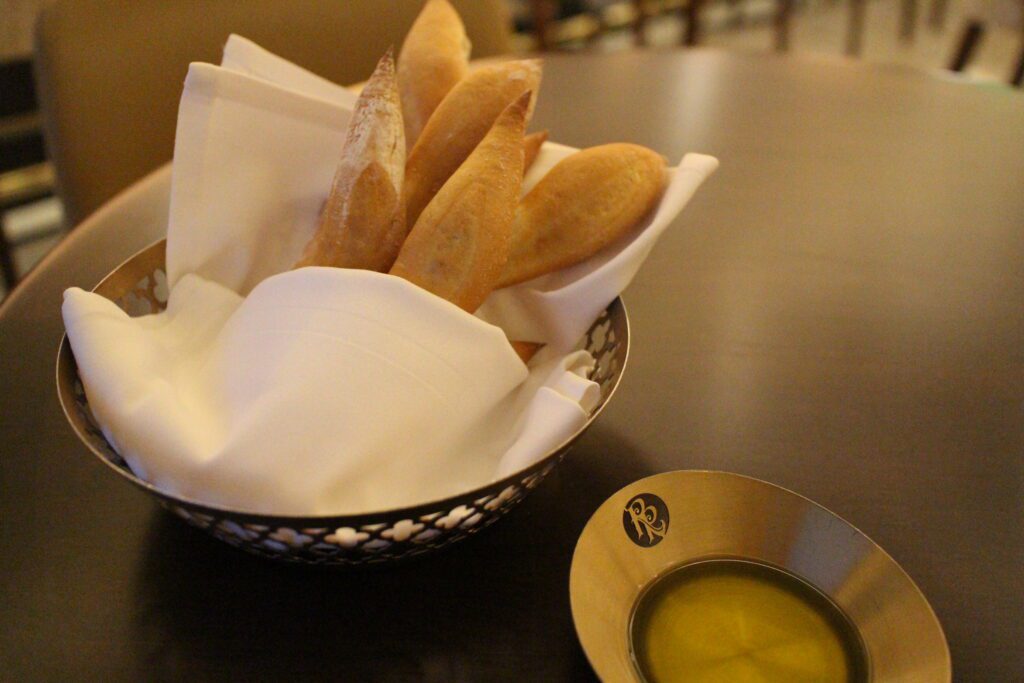 Topolino's Terrace bread service in a basket with a side of olive oil in a gold container.