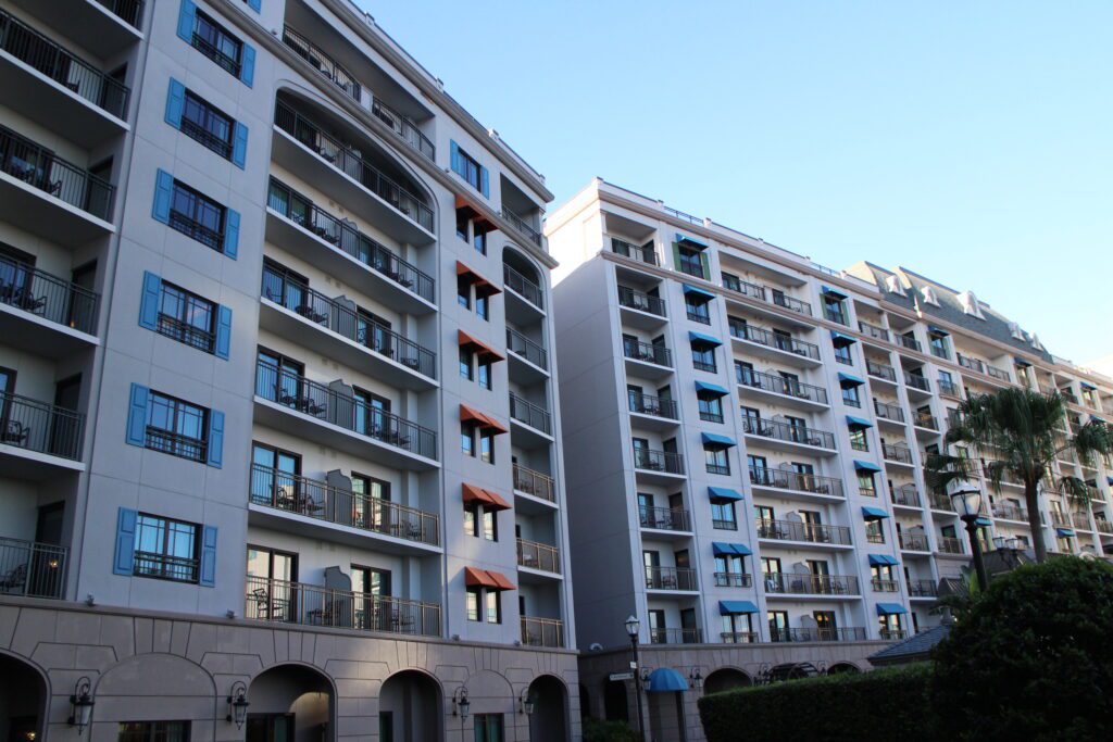 A tall gray Disney's Riviera Resort hotel building with blue shutters and orange awnings. | Where can you use DVC resale points