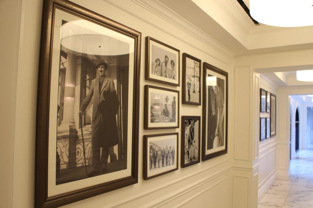 A gallery wall showcasing framed black and white images of Walt Disney's travels.