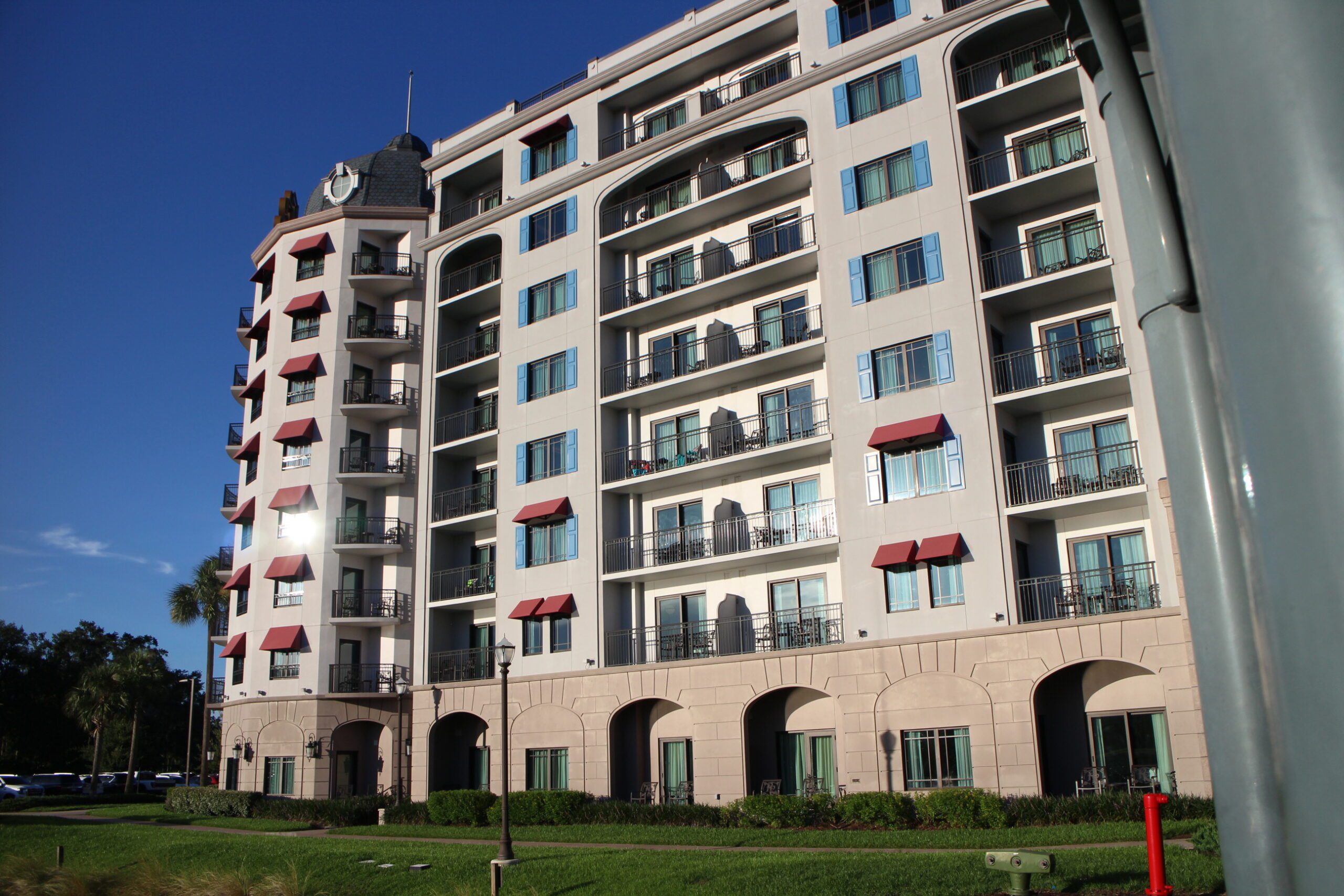 Disney's Rivera Resort building with gray walls and balconies and blue shutters and red shades by the windows.