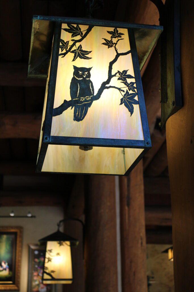 A craftsman style lantern with an owl cutout lit in black. The decor is one of the pros or cons of Copper Creek DVC resale depending on how you like this kind of National Park lodge inspired rustic aesthetic.