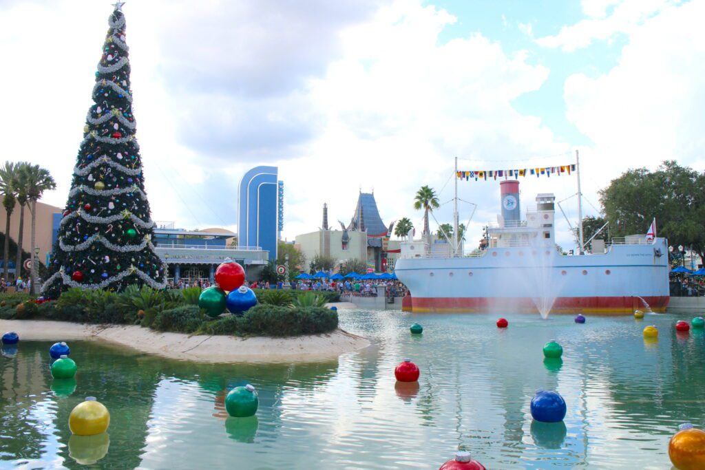 Hollywood Studios Christmas decorations, how the park looks for Jollywood Nights: Echo Lake filled with colorful floating bulbs and a giant Christmas tree rests at the shore.