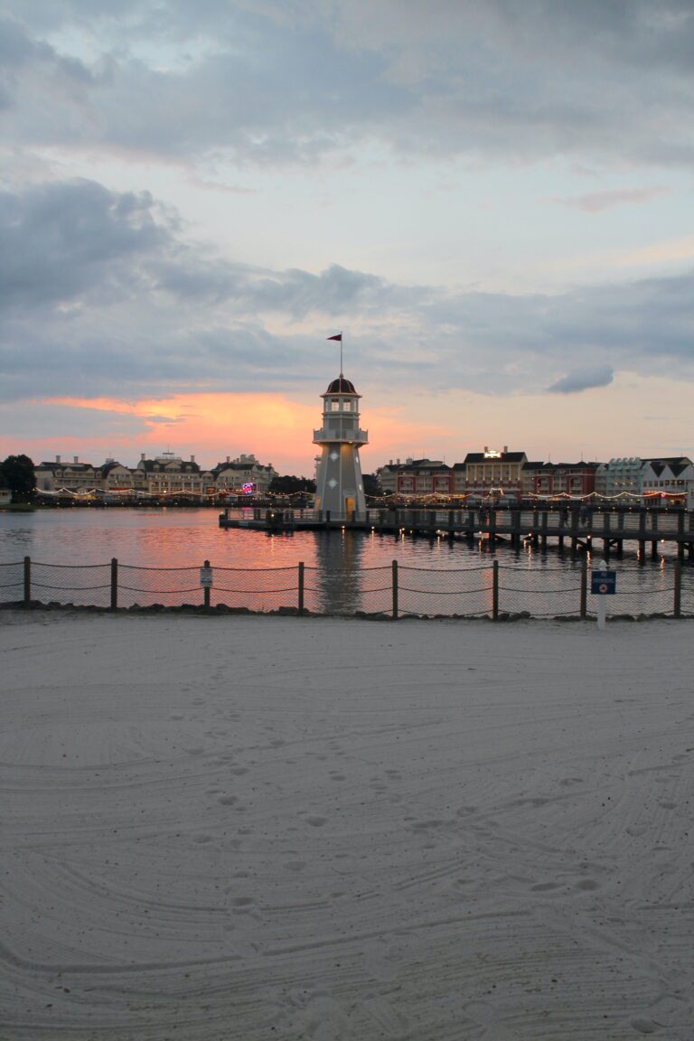 A sunset from the beach at Disney's Beach Club Villas with a small lighthouse in the distance.