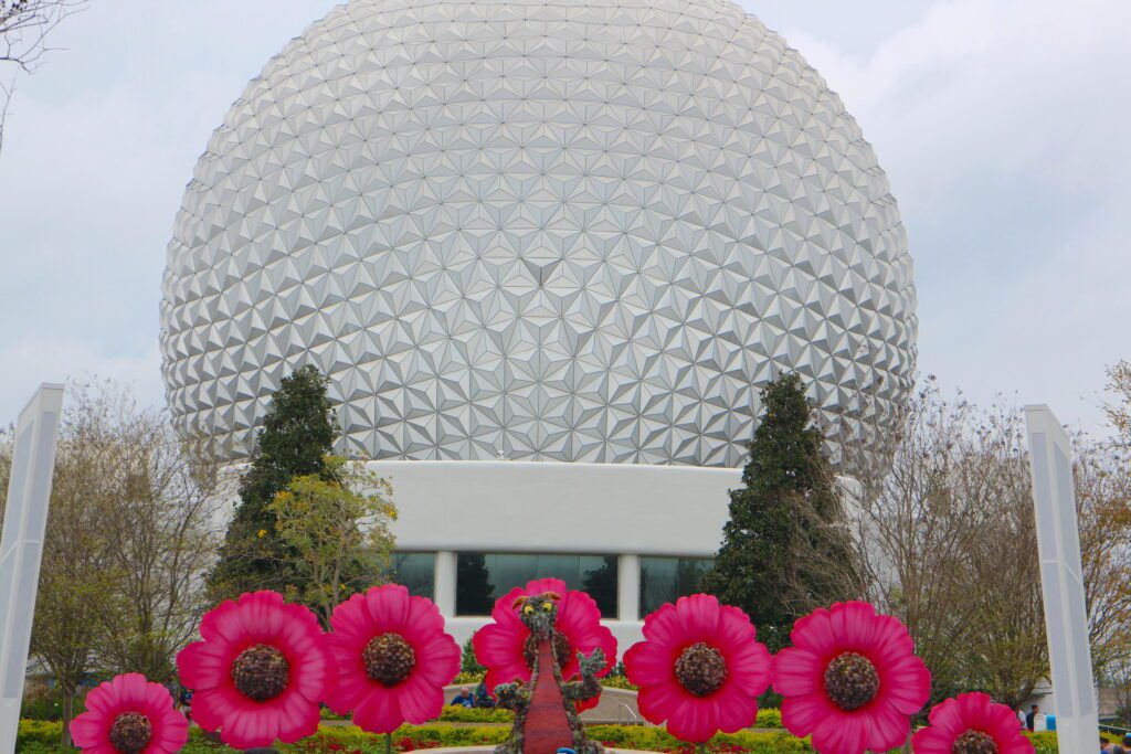 The Spaceship Earth geodesic sphere with pink flower ornamental statues and a Figment the dragon topiary.