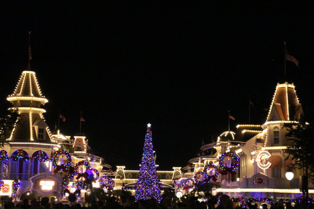 Mickey's Very Merry Christmas Party Main Street U.S.A. views with lights lining the street and a huge Christmas tree with colored lights at the end.